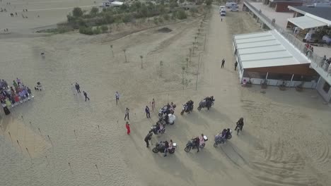 Die-Braut-Kommt-Auf-Dem-Rücken-Eines-Motorrads-Am-Strand-Zu-Ihrer-Hochzeit,-Umgeben-Von-Ihren-Freunden