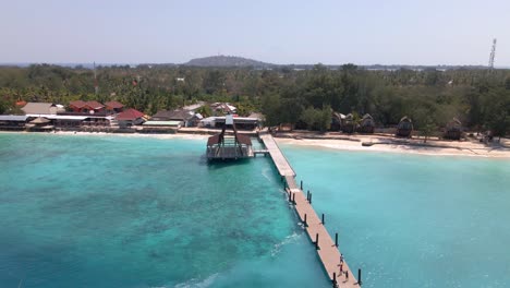 Epic-aerial-flight-through-house-of-Gili-Meno-Island-Pier-with-jetty,clear-water-and-tropical-beach