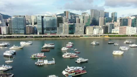 Hong-Kong-marina-with-anchored-boats-and-Kwun-Tong-area-buildings,-Low-angle-aerial-view