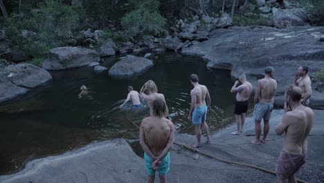Gruppe-Von-Männern,-Die-Auf-Dem-Felsen-Stehen-Und-Sich-Darauf-Vorbereiten,-Im-Wasser-Zu-Tauchen-Und-Zu-Schwimmen---Mount-Byron,-Queensland,-Australien