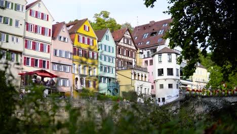 Süße-Kleine-Alte,-Farbenfrohe-Gebäude-Der-Deutschen-Flussstadt-Tübingen-Mit-Bürgern,-Die-Sich-Entspannen-Und-Entspannen,-Während-Sie-Die-Sonne-Genießen