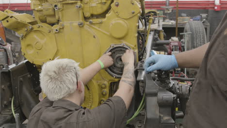 Pair-of-diesel-mechanics-work-together-on-a-heavy-industrial-engine-rebuild-slider-shot-male-and-female-blue-collar-labor