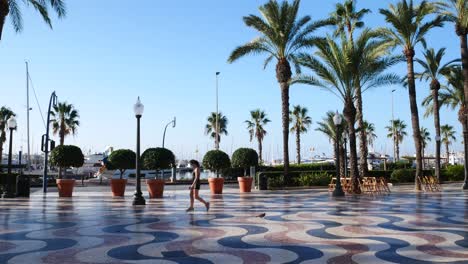 Toma-Cerrada-De-Una-Mujer-Caminando-Con-Una-Máscara-Higiénica-Frente-Al-Puerto-De-Alicante