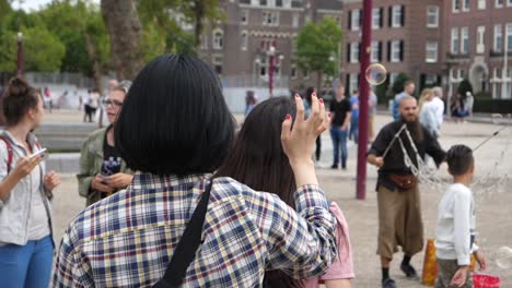 Slow-motion-footage-of-group-of-people-playing-with-bubbles-in-public-park,-Amsterdam,-Netherlands