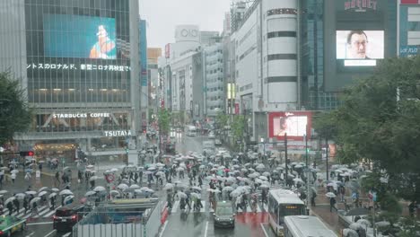 Szene-Am-Shibuya-Kreuzung-Mit-Gehenden-Menschen,-Die-An-Einem-Regnerischen-Tag-Regenschirme-Hochhalten