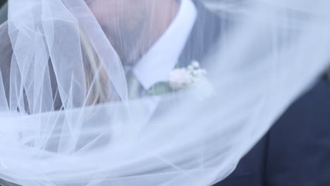 Bride-and-groom-tender-embrace-under-veil-slow-motion
