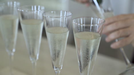 Placing-glass-of-champagne-down-filling-glasses-at-wedding-reception
