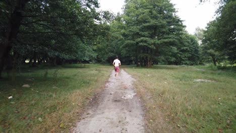 Young-Caucasian-male-running-in-forest-on-a-trail-in-summer