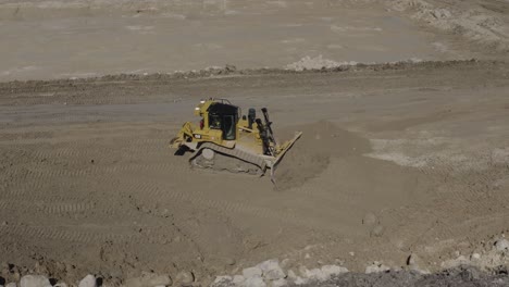 Aerial-circling-shot-of-a-John-Deere-450D-excavator-loading-dirt-into-a-rock-truck-on-a-construction-site