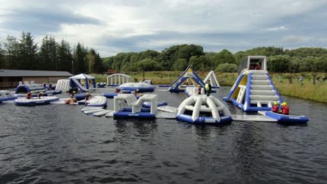 Bunte-Aufblasbare-Hindernisse-Auf-Dem-Wasser-Im-Splash-Valley-Aqua-Park-In-Rathdrum,-Wicklow,-Irland-Mit-Menschen,-Die-Spaß-Haben-–-Totale