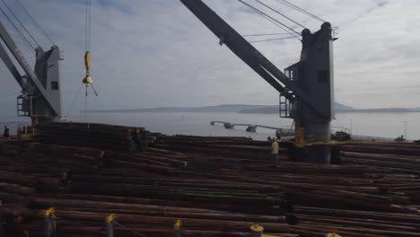 4K-drone-footage-pan-of-large-ship-being-loaded-with-logs-by-cranes