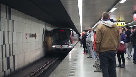 Metro-train-arriving-to-Florenc-platform-full-of-waiting-people-in-Prague,-Czech-Republic