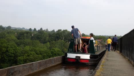 Narrow-canal-boat---tourists-crossing-over-scenic-Pontcysyllte-aqueduct-tranquil-countryside-rural-scene