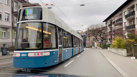 Following-Flexity-Tram-driving-and-arriving-at-Tram-stop-Burgwies-in-Zürich-Switzerland