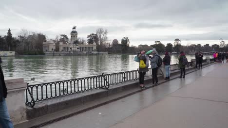 Gente-En-El-Paseo-Marítimo-Viendo-La-Histórica-Estatua-Ecuestre-Del-Rey-Alfonso-Xii-En-El-Parque-Del-Buen-Retiro,-Madrid,-España---Plano-General