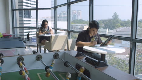 Static-Shot-Of-Employees-Working-Inside-Lounge-Of-A-Modern-Corporate-Office-With-Large-Window