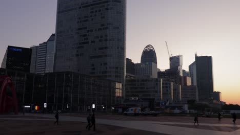 La-Defense-wide-panning-shot-during-early-morning-with-few-people-walking-by-in-Puteaux-near-Paris