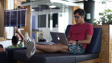 Millennial-Sitzt-In-Einem-Trendigen-Startup-Büro-Auf-Modernen-Möbeln-Und-Arbeitet-An-Einem-Laptop