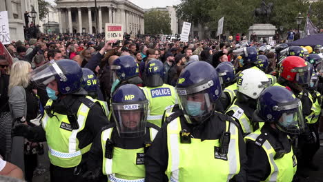 Riot-police-wearing-protective-face-masks-are-surrounded-by-angry-protestors-on-an-anti-mask-and-anti-lockdown-demonstration-promoting-Coronavirus-and-QAnon-conspiracy-theories