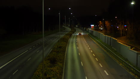 Black-car-driving-alone-on-an-empty-highway-at-night
