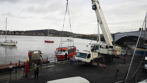 Telescopic-crane-vehicle-lifting-heavy-fishing-boat-on-Conwy-Wales-harbour