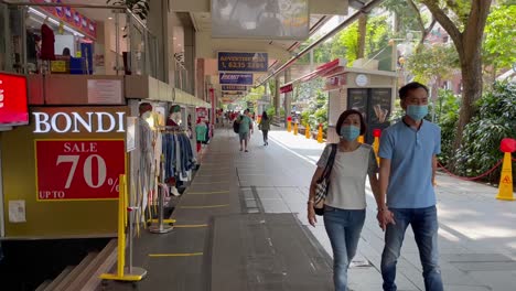 People-wearing-mask-walking-along-Orchard-Road,-Singapore