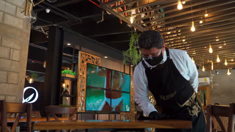 Waiter-cleaning-wood-table-in-Restaurant-Bar-for-sanitize-protocol-covid
