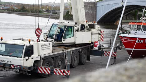 Telescopic-industrial-crane-vehicle-lifting-fishing-boat-on-Conwy-Wales-harbour-dolly-left