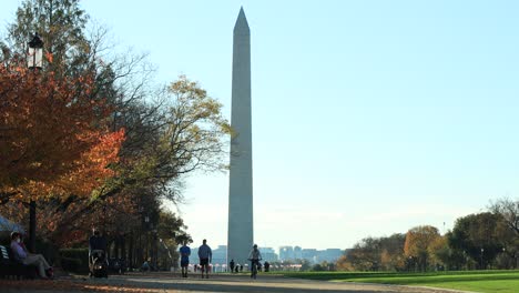 Fußgänger,-Die-An-Sonnigen-Tagen-Durch-Den-Park-Mit-Bunten-Bäumen-Spazieren,-Und-Das-Washington-Monument-Im-Hintergrund