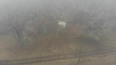 campervan-camping-in-forest-fog-drone-aerial-descend-tilt-reveal