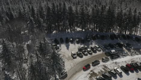 Estacionamiento-De-Automóviles-En-El-Complejo-Invernal-De-Kope-En-Las-Montañas-Pohorje-Que-Conducen-Al-Bosque,-Tiro-De-Revelación-De-Inclinación-Aérea-Hacia-Arriba