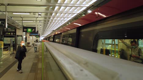 Hong-Kong-MTR-Underground-train-leaving-station,-with-passengers-boarding