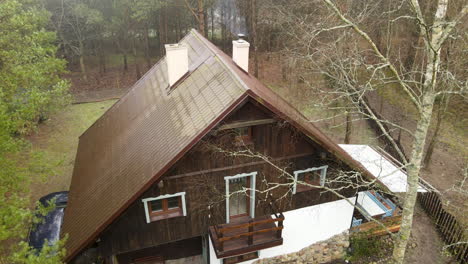 Langsamer-Start-Aus-Der-Luft-über-Einem-Alten-Traditionellen-Polnischen-Braunen-Holzhaus-Im-Wald-Bartoszylas