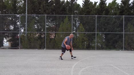 Cinematic-shot-of-a-man-practicing-basketball-moves-on-an-outdoor-court