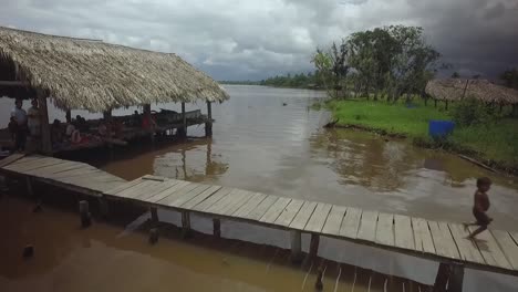 Drohnenansicht-Einer-Gruppe-Indigener-Warao-Kinder,-Die-In-Einem-Schwimmenden-Haus-Im-Orinoco-Fluss-Laufen