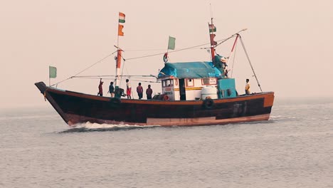 Pequeño-Barco-De-Pescadores-Navegando-En-Medio-Del-Océano-Con-Pescadores-Preparándose-Para-Atracar-Durante-La-Puesta-De-Sol-Con-Pequeñas-Olas-Tranquilas-Y-Regresando-A-Casa-En-Un-Fondo-De-Video-De-Clima-Brumoso-En-Mov-En-Full-Hd