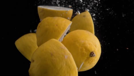Limones-Cayendo-Al-Agua-En-Cámara-Superlenta,-Fondo-Negro,-Muchas-Burbujas-De-Aire,-4k240fps