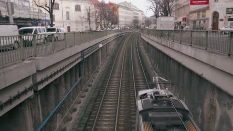 Metro-passing-by-on-tracks,-in-Vienna,-Austria,-with-the-city-and-the-traffic-in-the-background