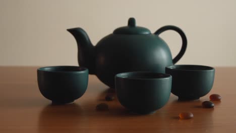 minimal-background-of-a-green-japanese-tea-set-with-steam-coming-out-of-the-cups,-on-a-wooden-table,-with-some-stones-around
