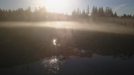 Aerial-view-of-Sunbeam-reflections-shining-through-mist-over-lake
