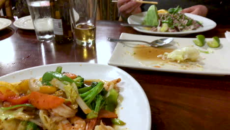 Mouthwatering-tasty-fresh-Thai-food-vegetable-spicy-dish-with-shrimp-served-at-a-restaurant-with-more-food-on-the-table