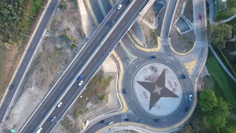 AERIAL-FOOTAGE---birds-eye-view-of-roads-and-roundabouts-with-cars-driving-on-them