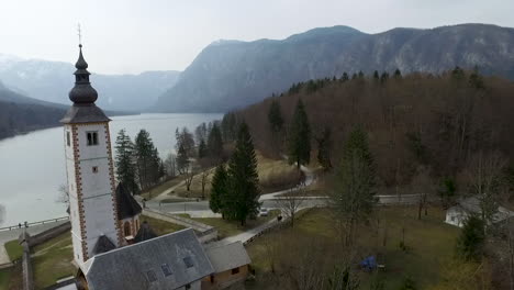 Drone-view-of-bridge-and-church-from-the-Bohinj-lake,-Slovenia