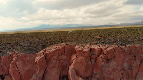 Filmische-Luftaufnahme-Eines-Einsamen-Autos-Auf-Einer-Straße-In-Der-Nähe-Einer-Schlucht-In-Der-Atacama-Wüste-Bei-Sonnenuntergang