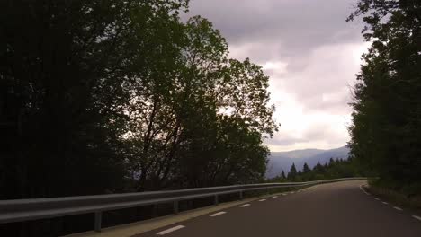 Driving-on-a-winding-road-with-a-view-to-the-wide-valley,-Bucegi-mountains,-Rumania