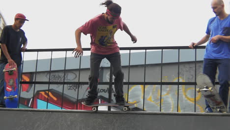 Skater-performs-the-BS-Axle-Stall-trick,-on-a-wooden-ramp,-while-others-are-waiting-for-their-turn