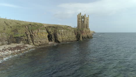 Aerial-rising-shot-moving-along-the-coastline-towards-Keiss-Castle-on-a-sunny-day,-Caithness,-Scotland