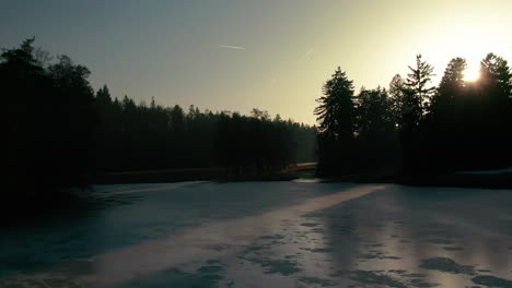 Winter-See-Drohne-Flug-Antenne-Gefrorenes-Wasser-Wald-Kiefern-Sonnenuntergang-Sonnenlicht-Lichtstrahlen-Pruhonice-Tschechien