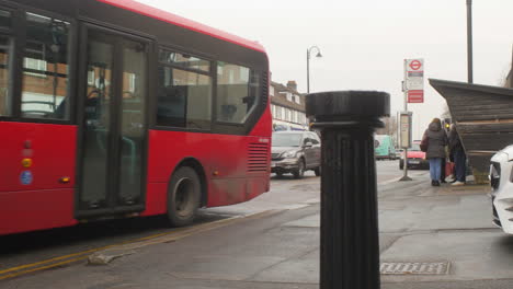 Autobús-Inglés-Rojo-Saliendo-De-Una-Parada-De-Autobús