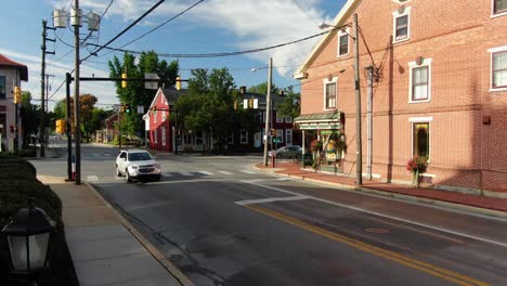 Low-dolly-forward-establishing-shot-of-a-busy-intersection-in-Small-Town-America,-bank,-general-store,-historic-homes